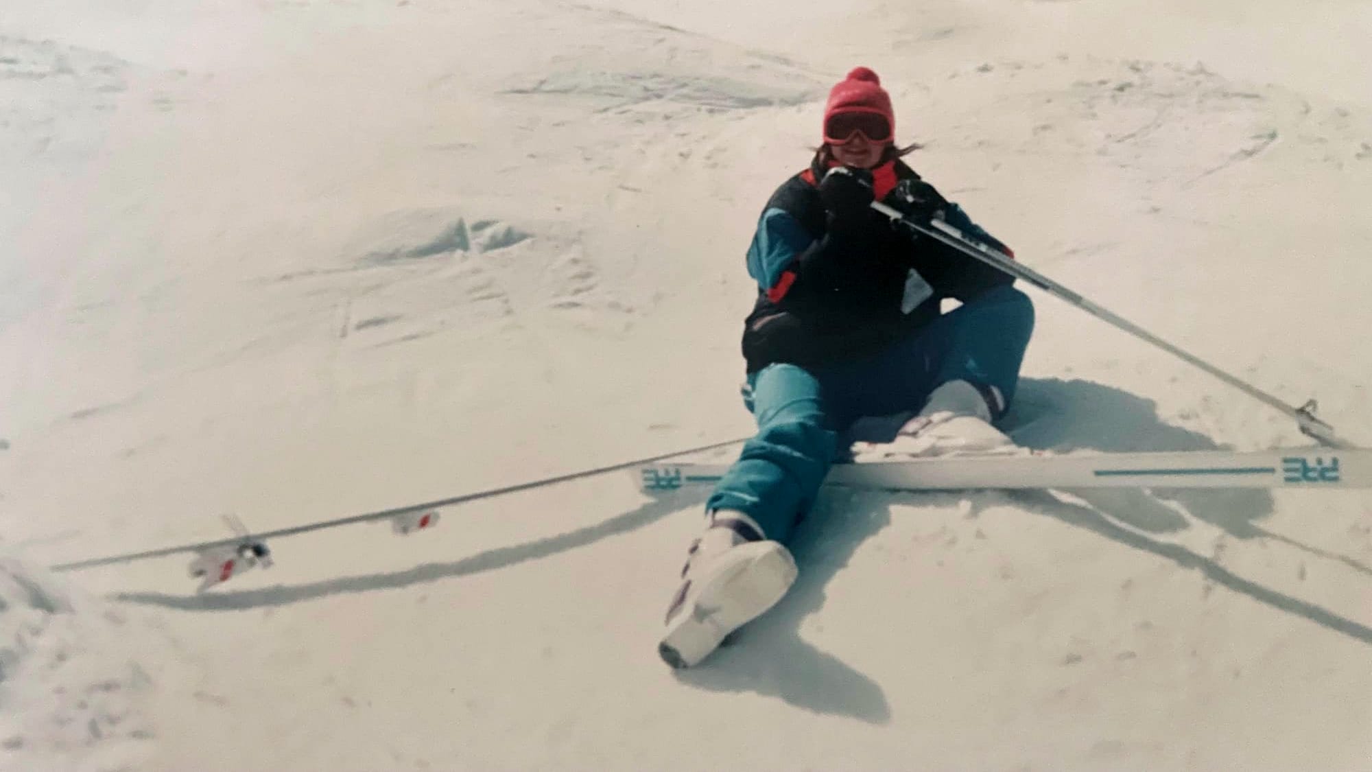 Woman sitting on ski hill with 1 ski off