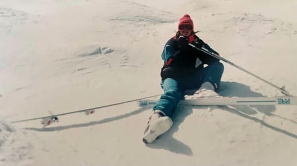 Woman sitting on ski hill with 1 ski off