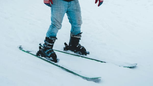 Man wears faded blue jeans while skiing on snow.