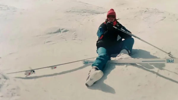 Woman sitting on ski hill with 1 ski off